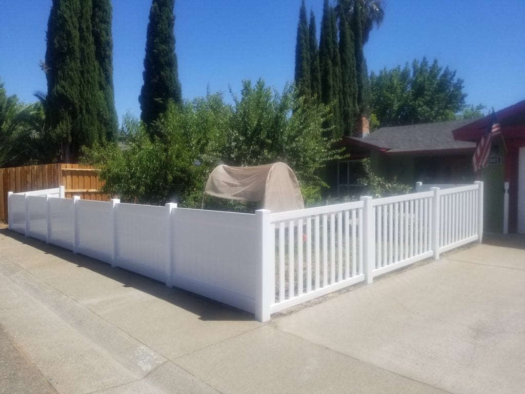 white vinyl closed picket fence around a stone property