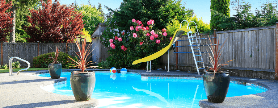a swimming pool in foreground with a yellow children's slide surrounded by a wooden fence in Sacramento, CA