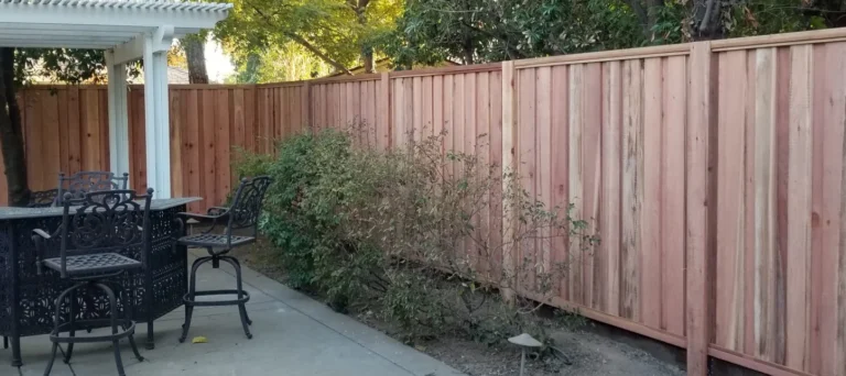 Wood privacy fence installation along a backyard patio with several vertical cedar fence panels