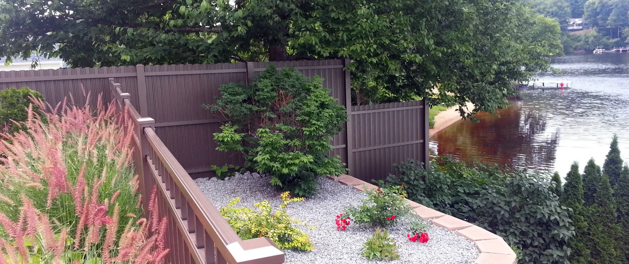 Brown privacy fence surrounding landscaped backyard near waterfront