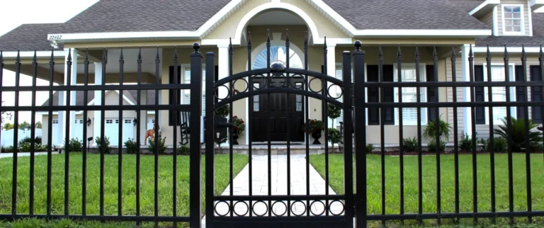 Decorative black aluminum driveway gate in front of suburban home entrance